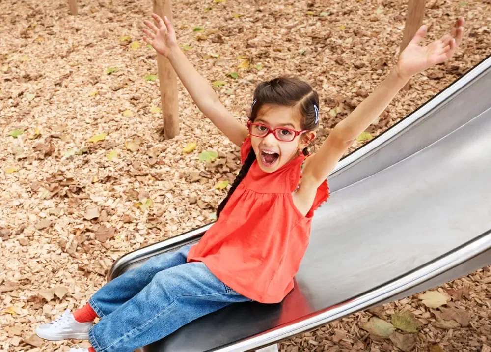 Ein Kind mit Brille am Fuß einer Rutsche